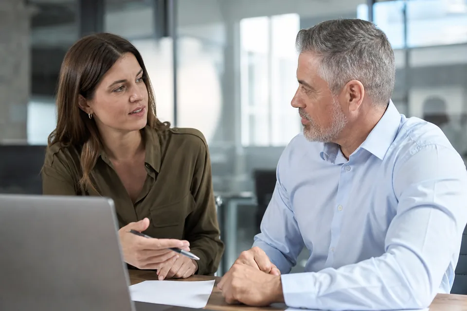 Recruiter and hiring manager discussing candidate interview scores at a desk